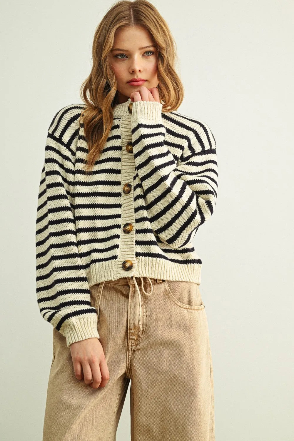 A cozy cropped knitted cardigan with bold black and cream striped pattern button front and wooden buttons
