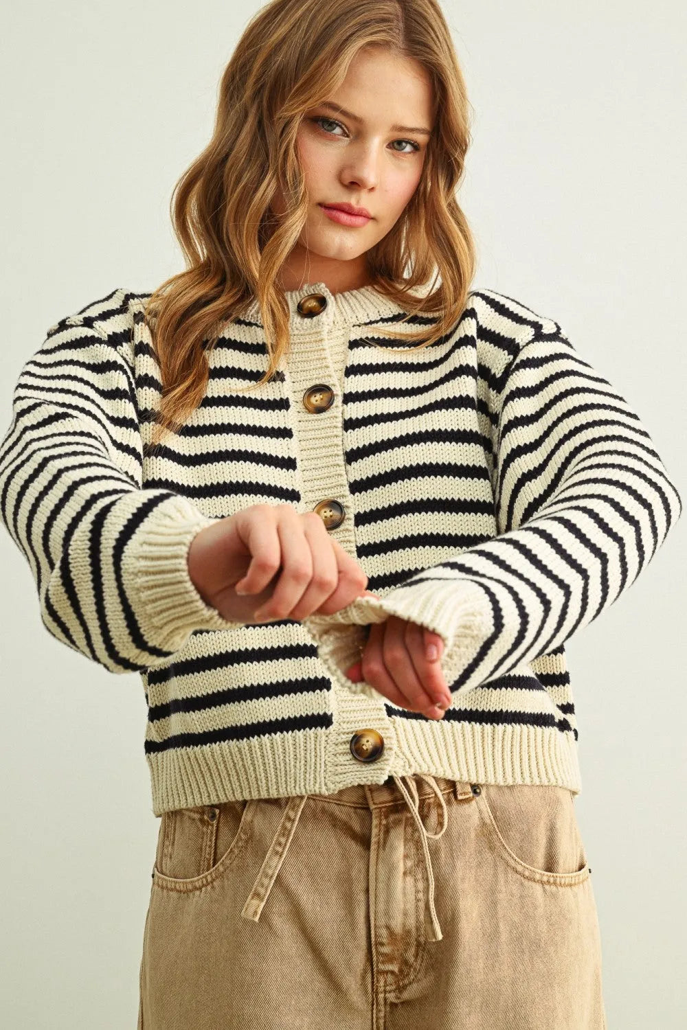 A cozy cropped knit cardigan with bold black and cream striped pattern button front and matching metallic buttons