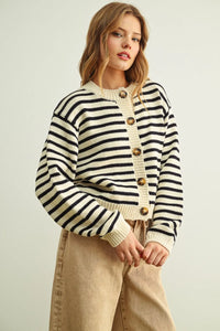 Cozy cropped knit cardigan featuring a bold cream and black striped pattern button front with gold-toned buttons