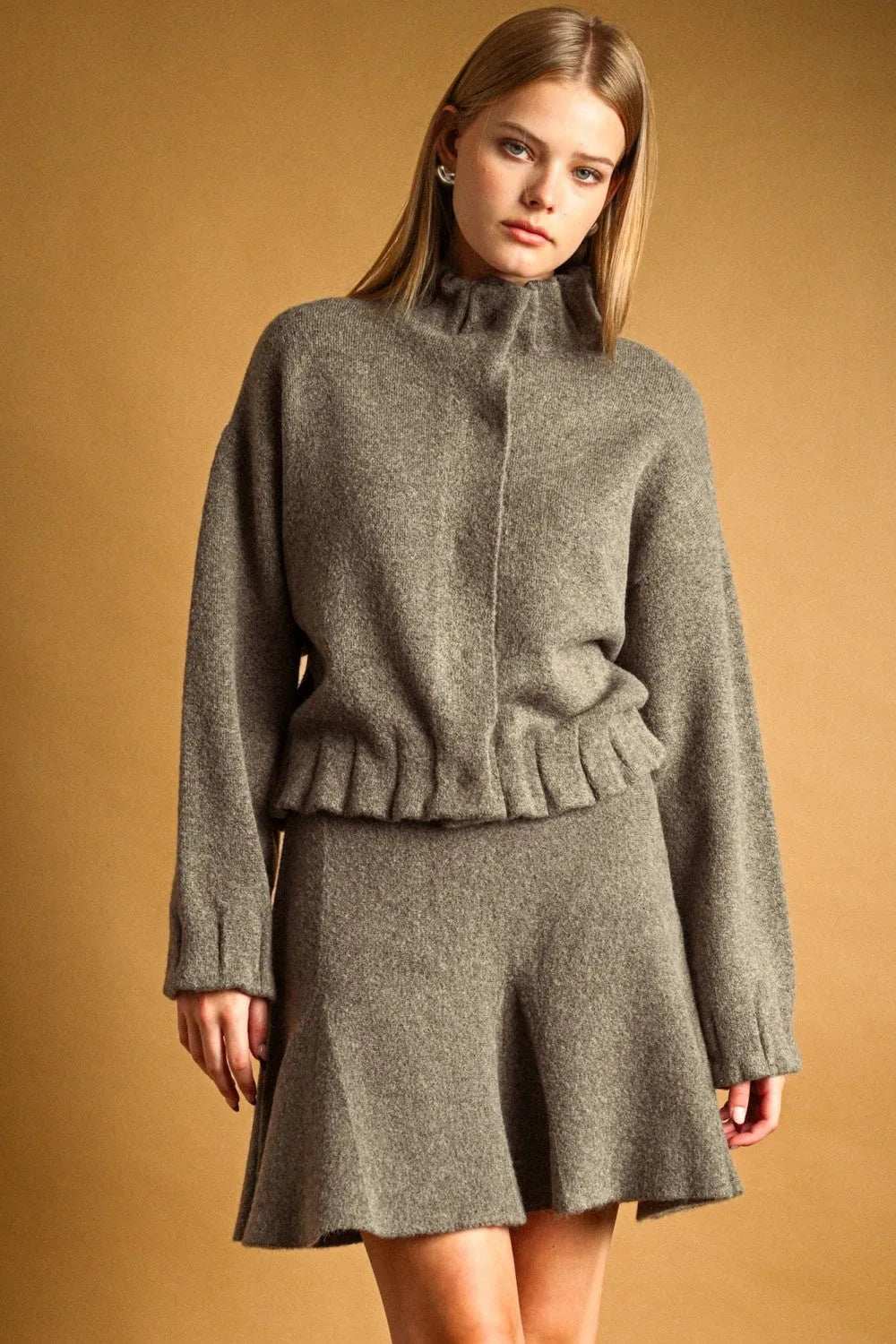 A cozy heather gray knit high neck button closure jacket with a ruffled hem and button closure jacket detail