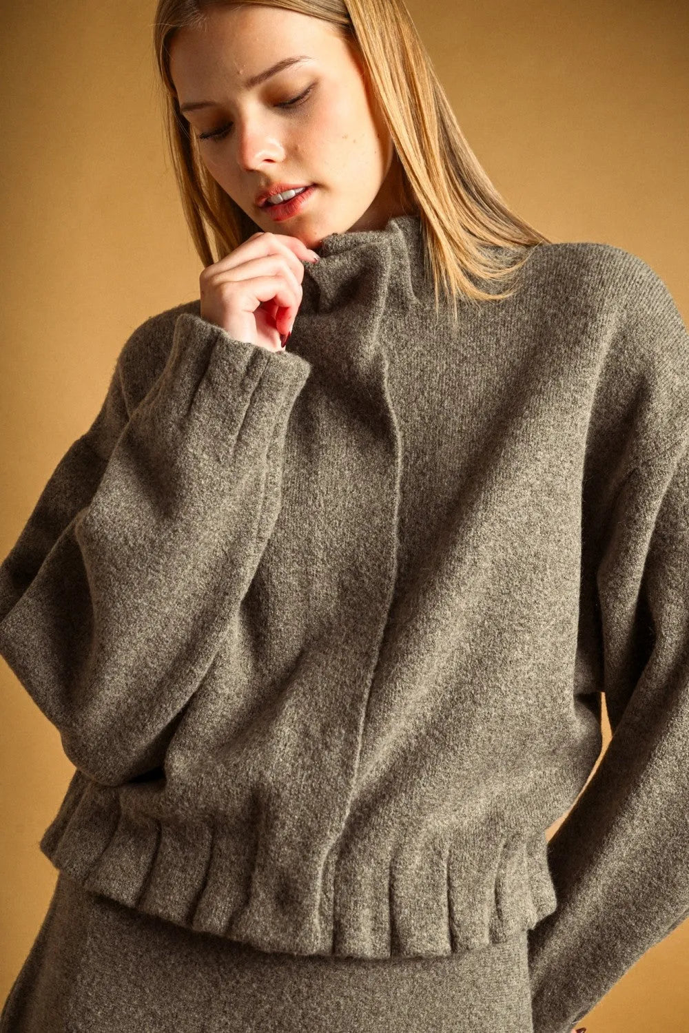 A cozy heather gray wool-blend sweater with high neck button closure and ruffled hem ideal for layering