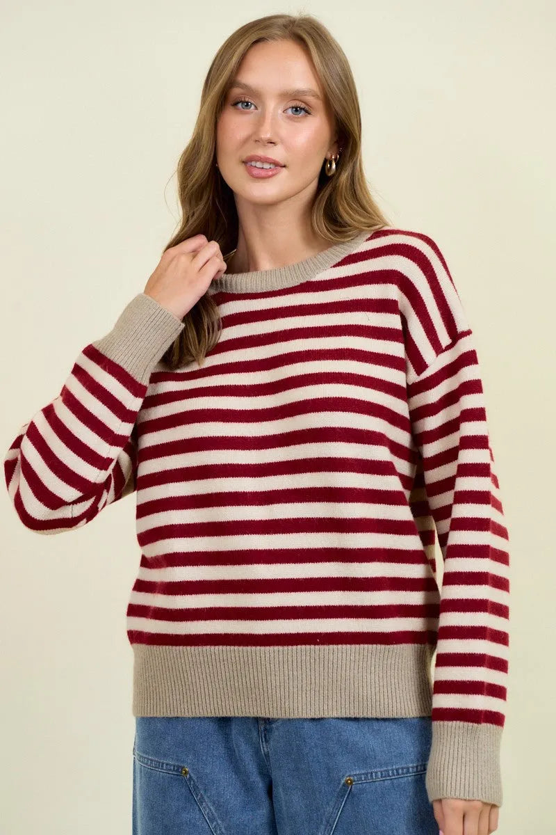 A cozy long-sleeved round neck stripe color block sweater with bold red and cream horizontal stripes and ribbed beige neckline