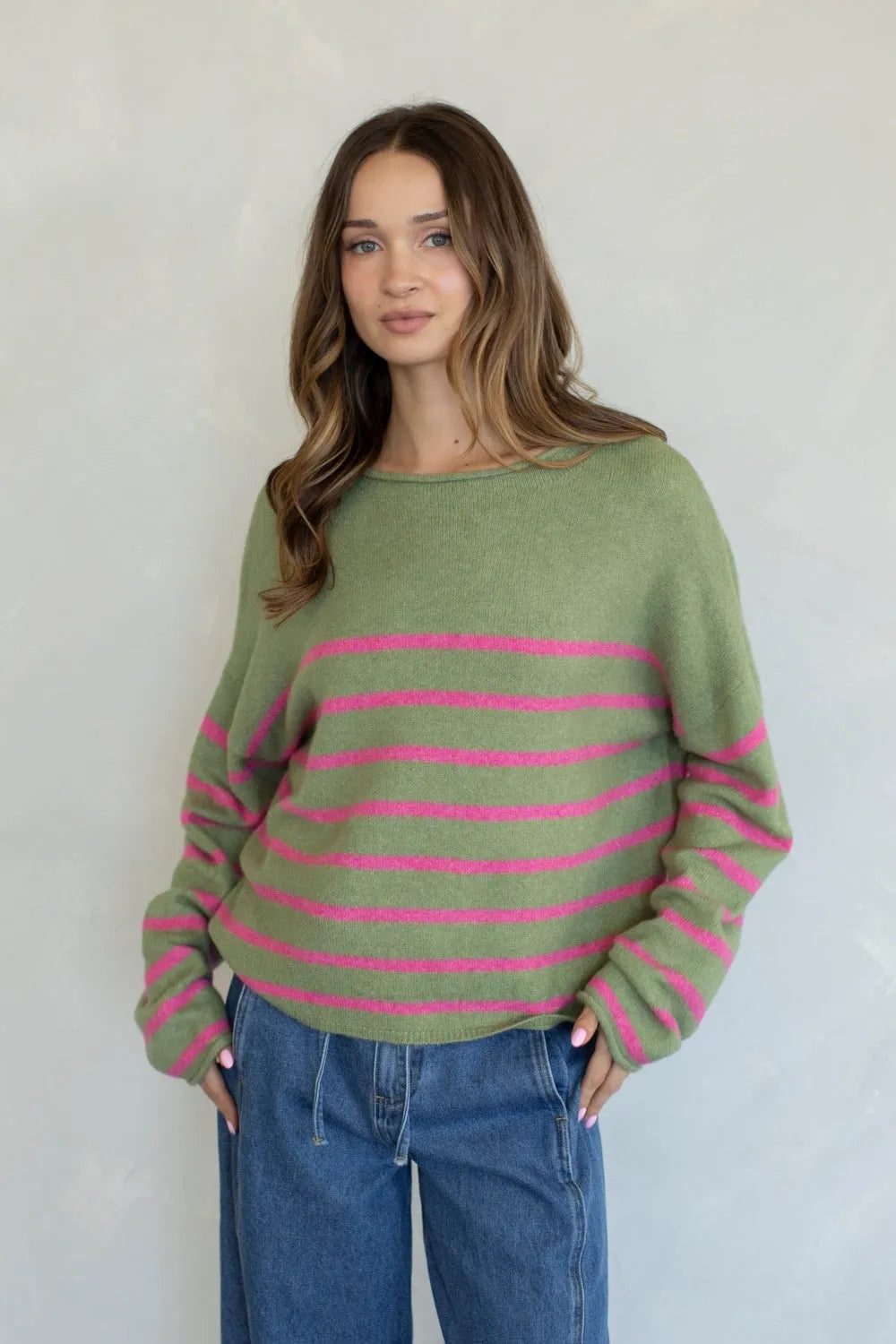 A cozy olive green quarter stripe piper pullover sweater with vibrant pink horizontal stripes and long sleeves