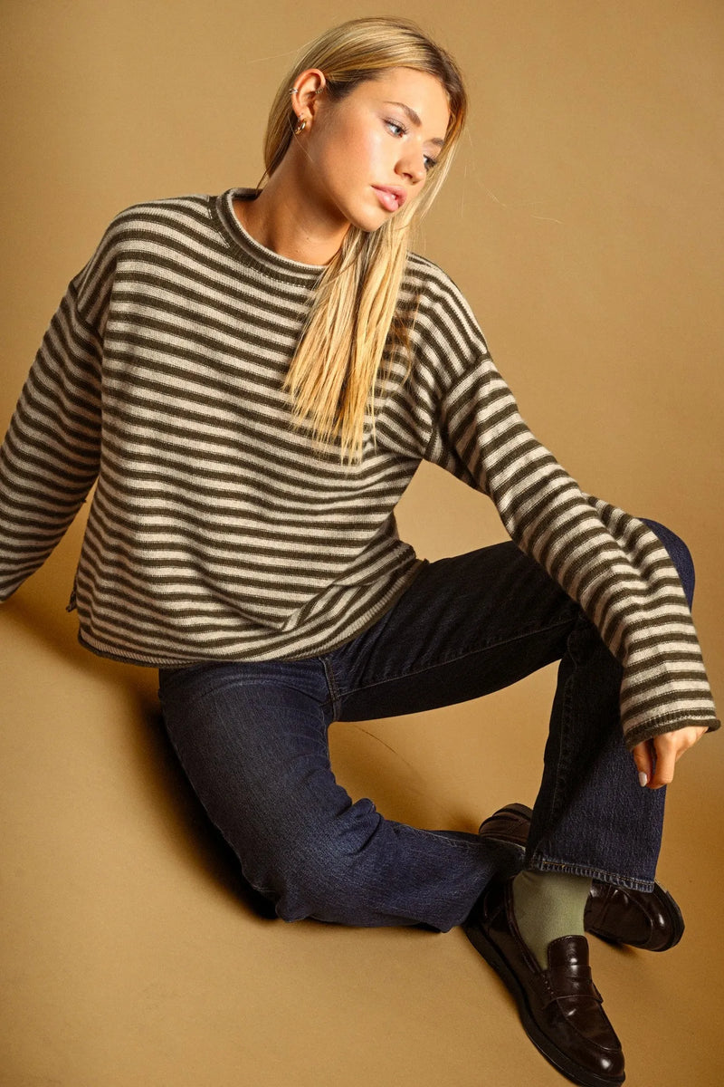 A cozy oversized sweater with a black and beige striped pattern and rolled neck detail for casual wear