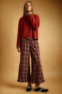 A cozy red knit cardigan featuring a plaid contrasted button closure and a plaid hemline
