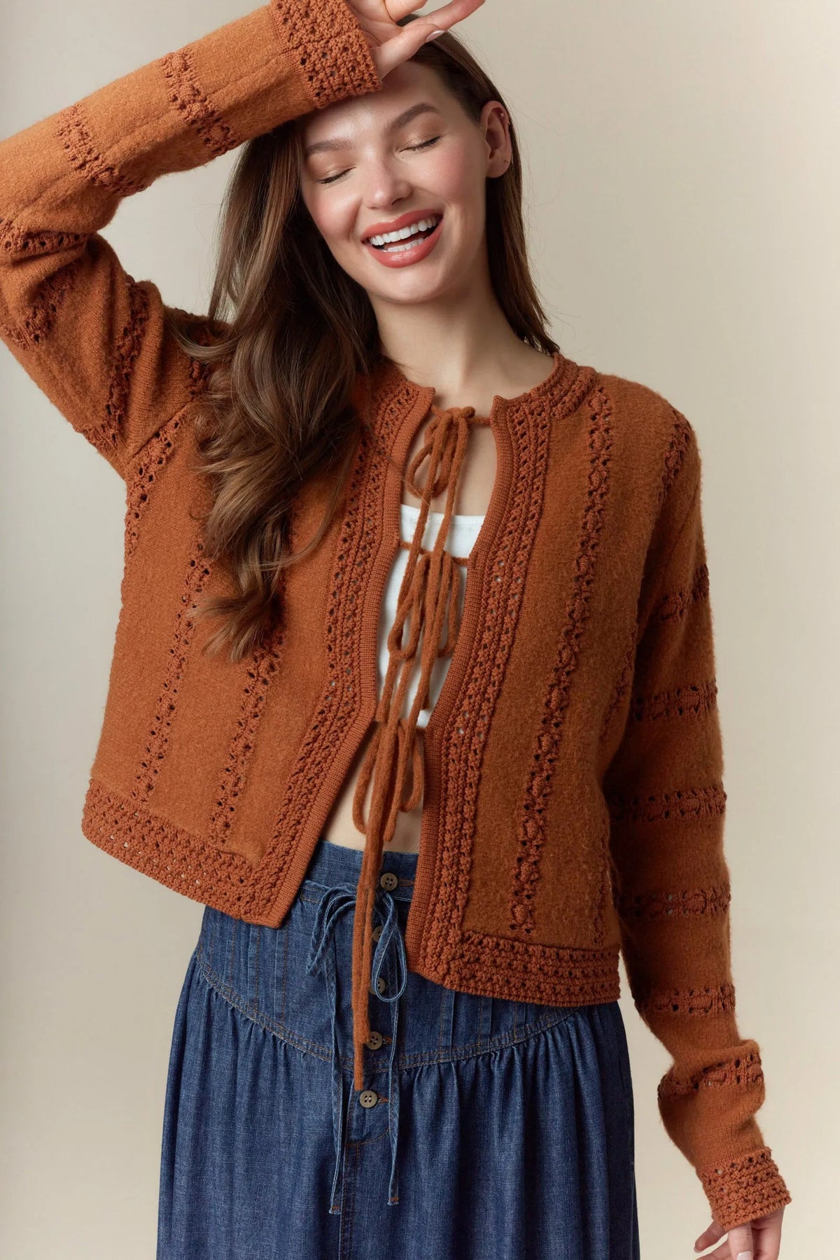 A cozy rust-colored knitted hole stripe bows front tie cardigan with intricate cable and lace patterns