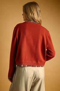 A cozy rust-red cropped knit sweater with ribbed hem and cuffs featured in a plaid contrasted button cardigan