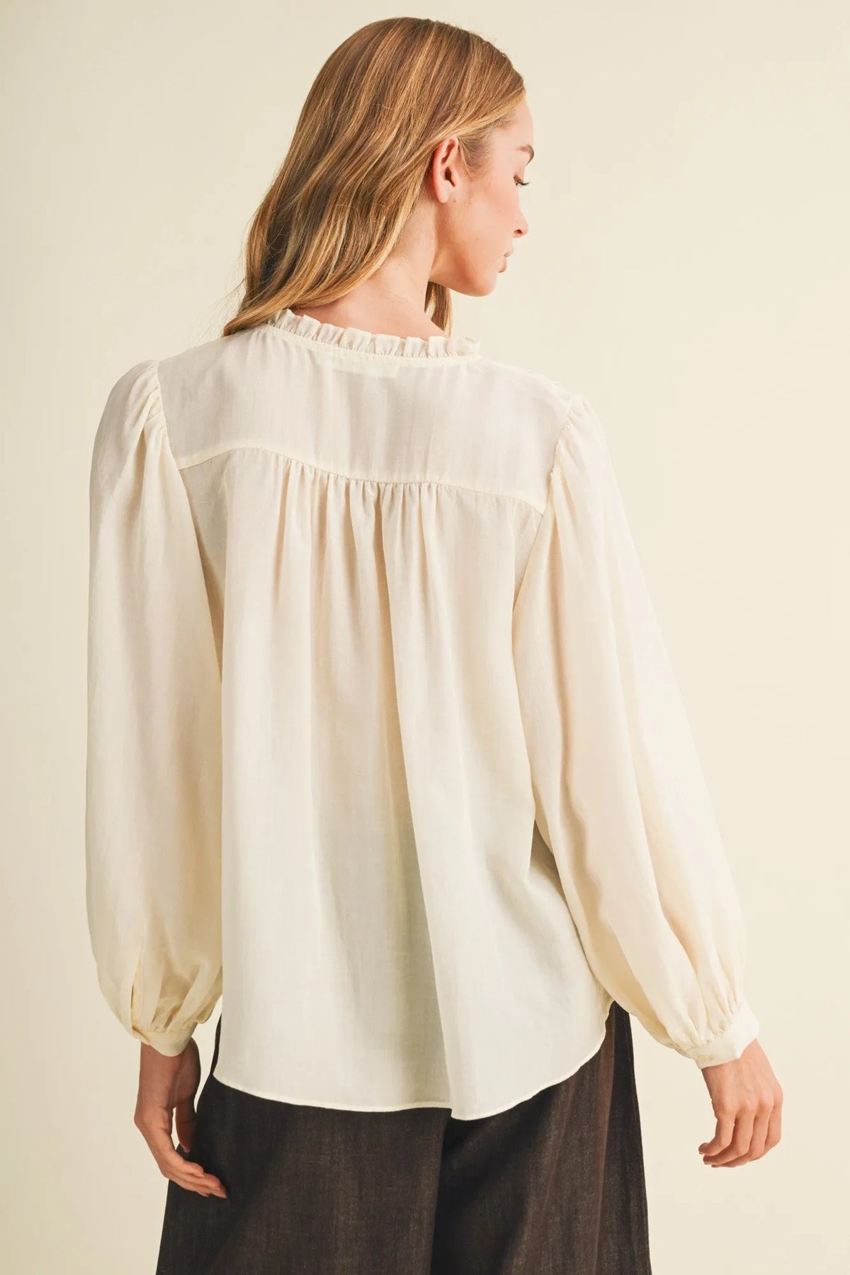 Cream-colored pintuck bib ruffle collar blouse with long puffed sleeves and a ruffled neckline