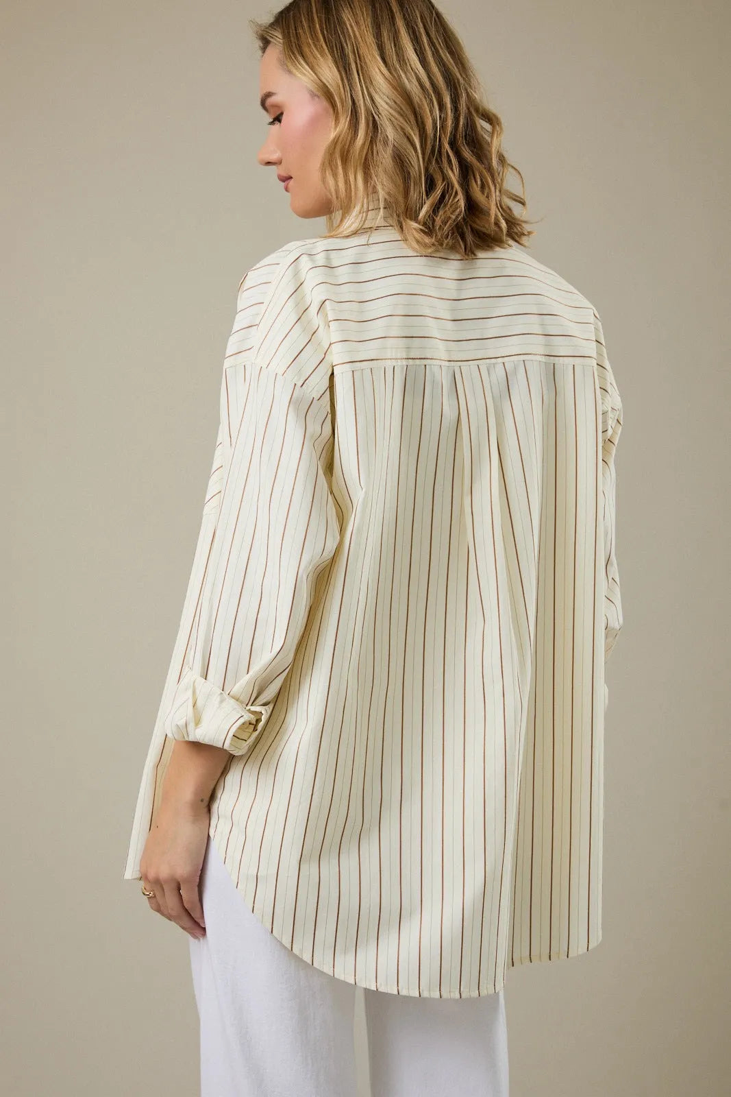 Cream-colored stripe classic button down shirt with thin brown stripes and rolled-up sleeves with gold buttons