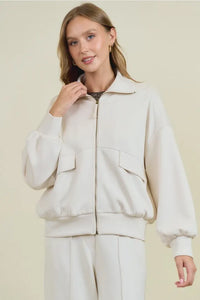 Cream-colored buttery soft flap jacket with full-length zipper, elasticated cuffs, and two front soft flap pockets