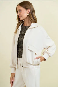 Cream-colored buttery soft flap pocket jacket with relaxed fit, ribbed cuffs and waistband, and front pockets