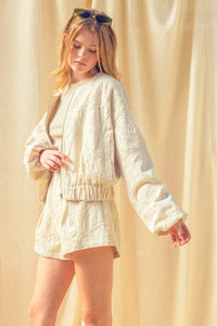 Cream-colored floral jacquard zip bomber jacket with intricate floral embroidery and elastic cuffs