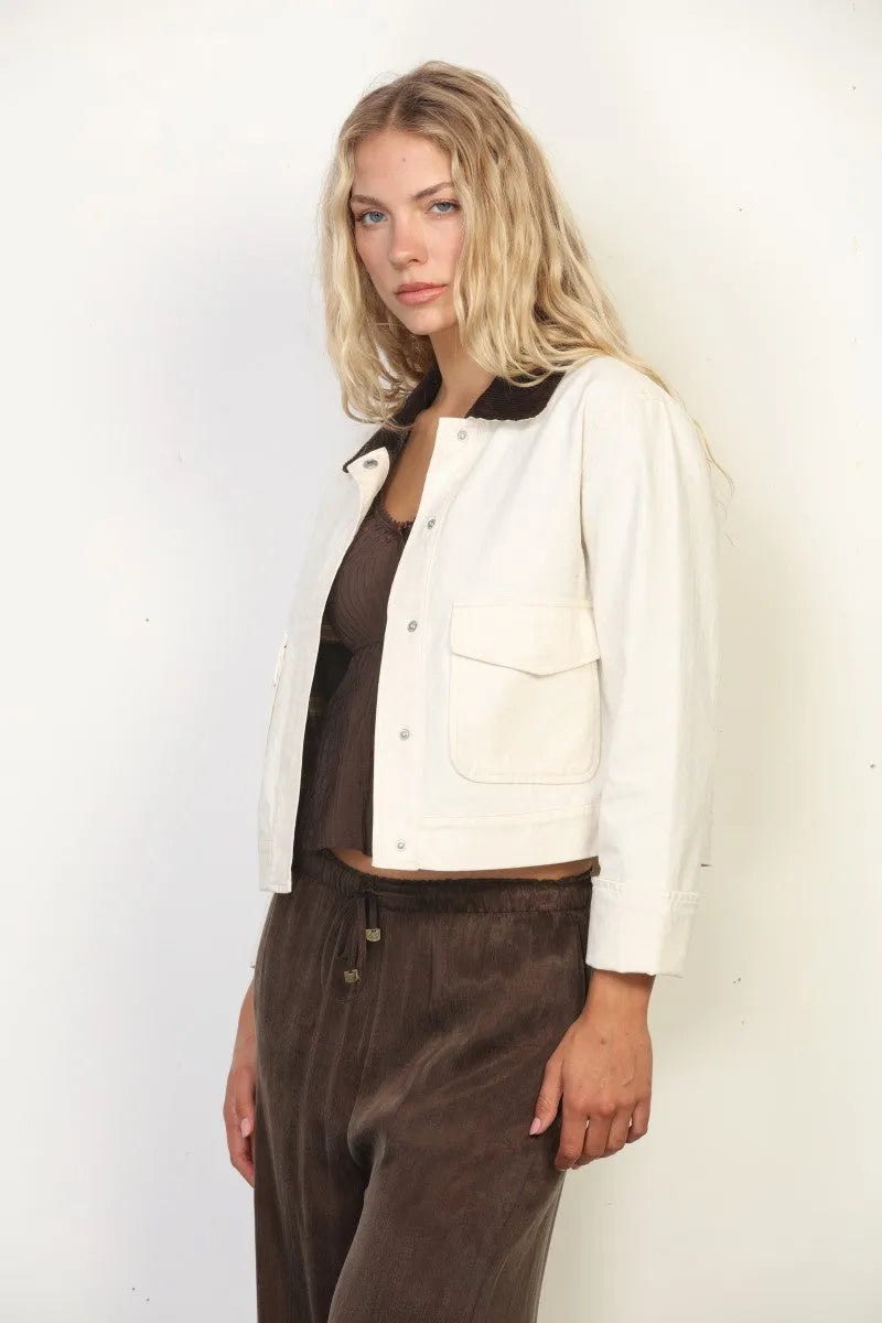 Cream-colored garment faded wash canvas barn jacket with black collar and button closures in bomber style