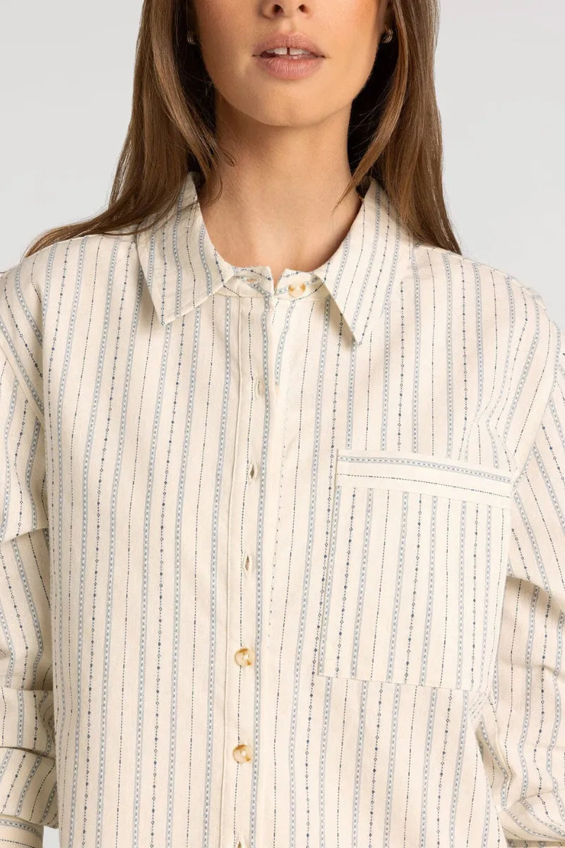 A cream-colored thread and supply lexington shirt with soft blue vertical stripes and chain-like seam detailing
