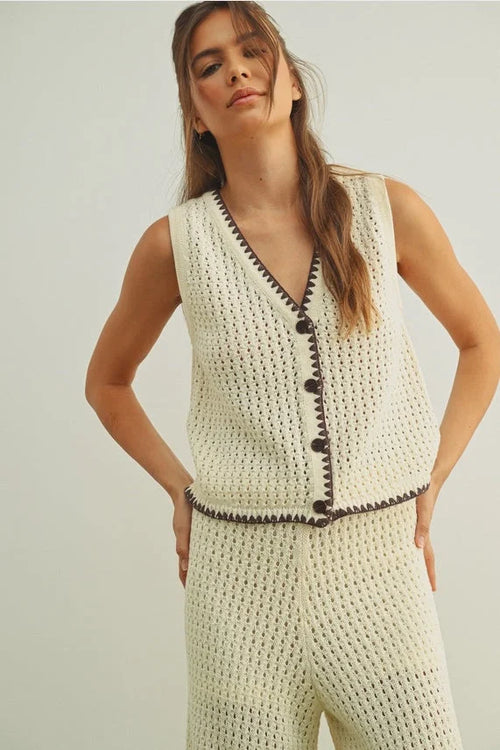 Cream-colored crochet knit vest with black button front accents
