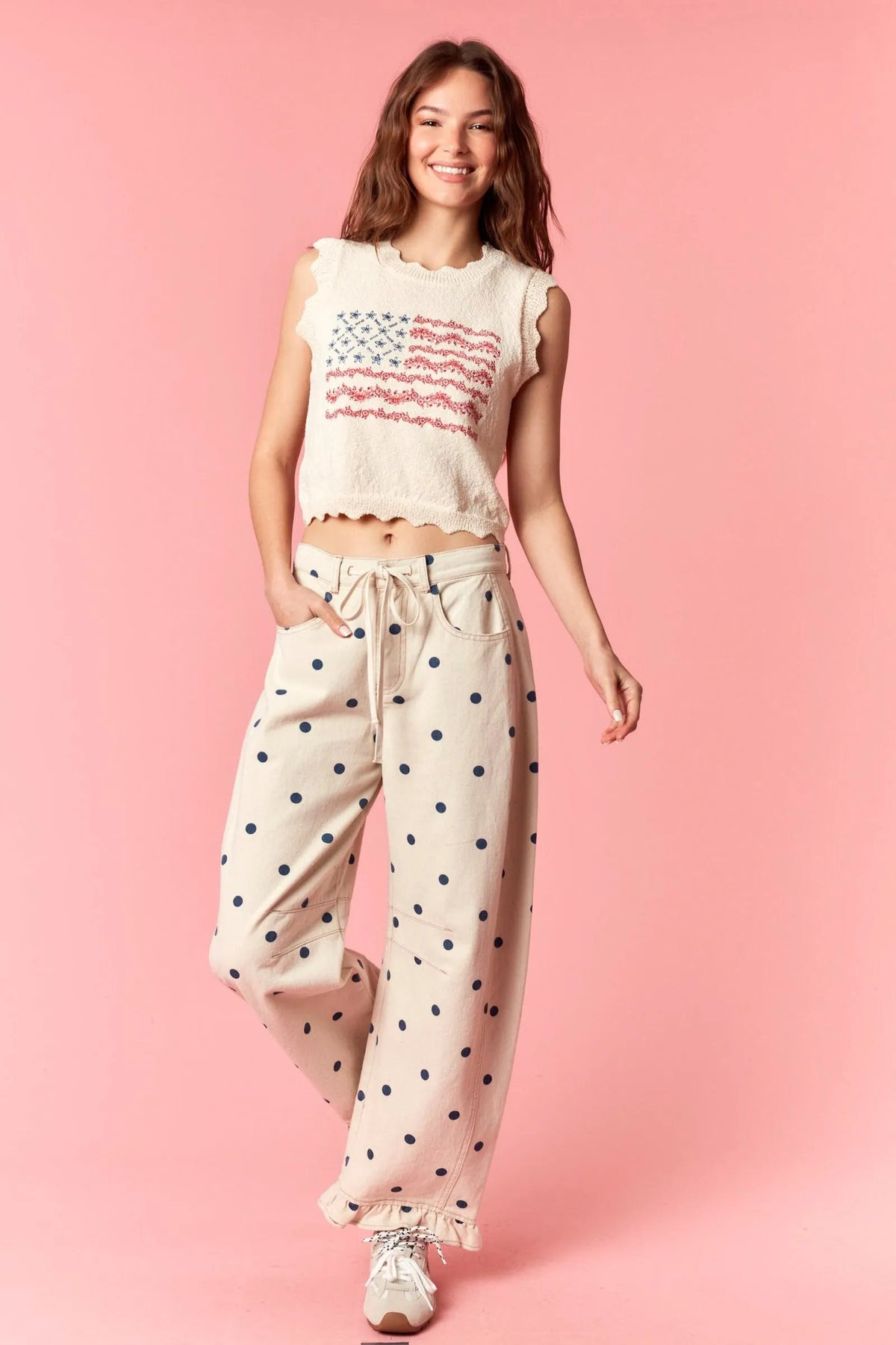 Cream-colored cropped top with red white and blue embroidered american flag paired with polka dot print ruffle hem twill pants