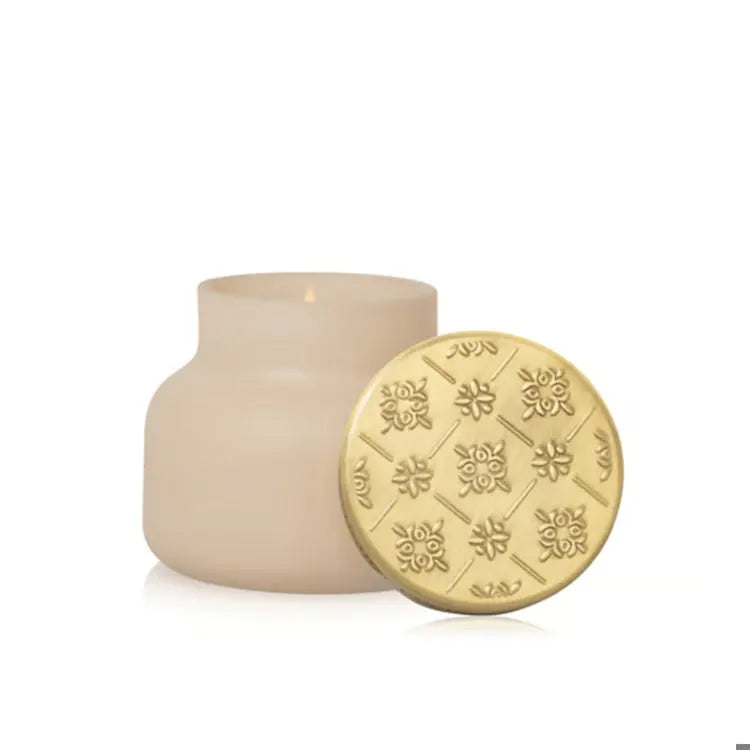 Cream-colored glass candle jar with gold-toned embossed floral lid from capri blue artisan terrazza velluto petite candle 8 oz