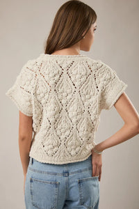 Cream-colored hand-knitted extended shoulder sweater top with intricate diamond lacework and slightly chunky knit texture