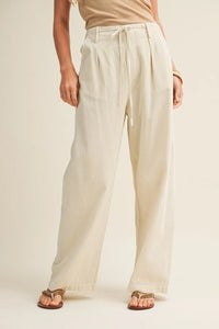 Cream-colored pleated waist wide leg dyed pants with high-waisted wide-leg cut and drawstring waist detailing