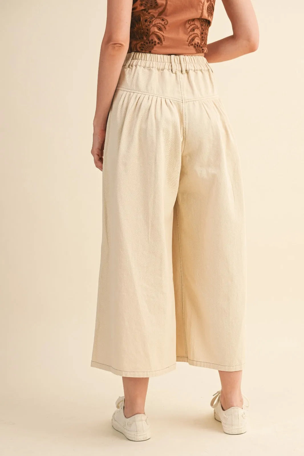 Cream-colored high rise super wide leg trousers with soft flowing fabric and elasticated waistband