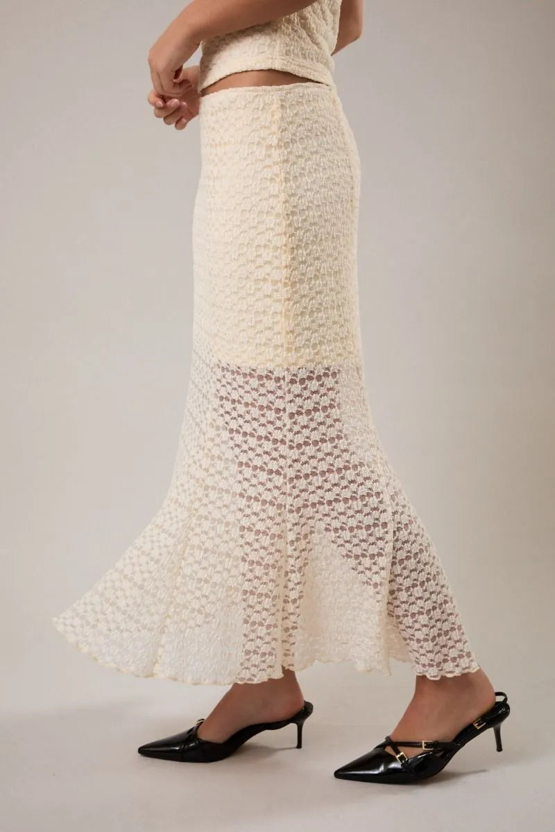 A cream-colored intricately crocheted mid rise midi half lined skirt with a flared hem and textured pattern