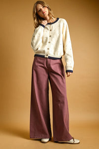 Cream-colored pointelle effect knit cardigan with navy blue trim and subtle embroidered details for elegant layering