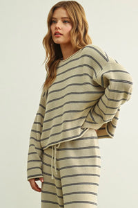 Cream-colored knit striped pattern long sleeve sweater with black horizontal stripes and a drawstring waistband