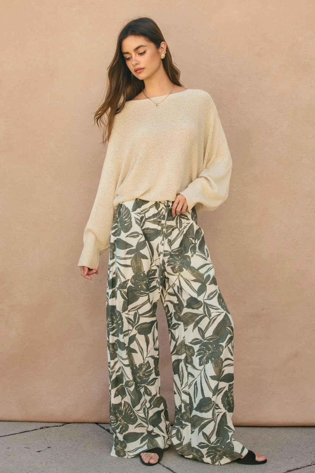 Cream-colored loose-fitting knit sweater with long sleeves styled with swaying palms wide leg pants for casual wear