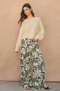 Cream-colored loose-fitting knit sweater with long sleeves styled with swaying palms wide leg pants for casual wear