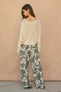 Cream-colored loose-fitting knit sweater with wide sleeves paired with swaying palms wide leg pants for relaxed style