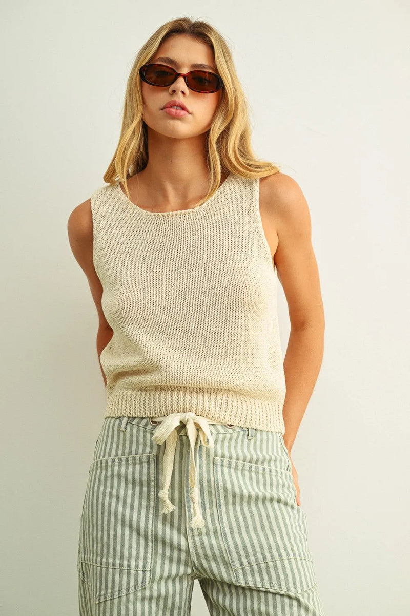 Cream-colored sleeveless roundneck knitted top with ribbed waistband and drawstring in soft yarn material