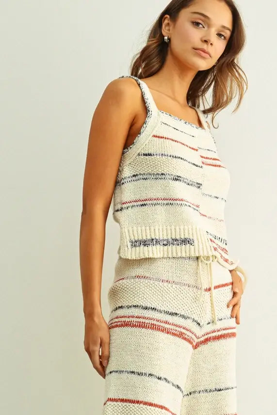 Cream-colored knitted tank top with multi color stripe pattern in red and navy blue featuring a ribbed hemline