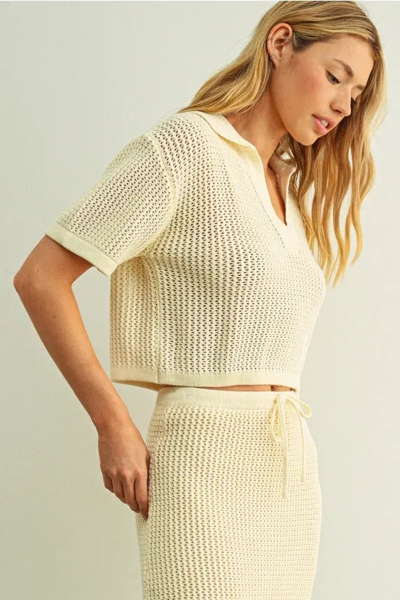 Cream-colored knitted two-piece set featuring a crochet v-neck collar top and matching high-waisted skirt with drawstring waist