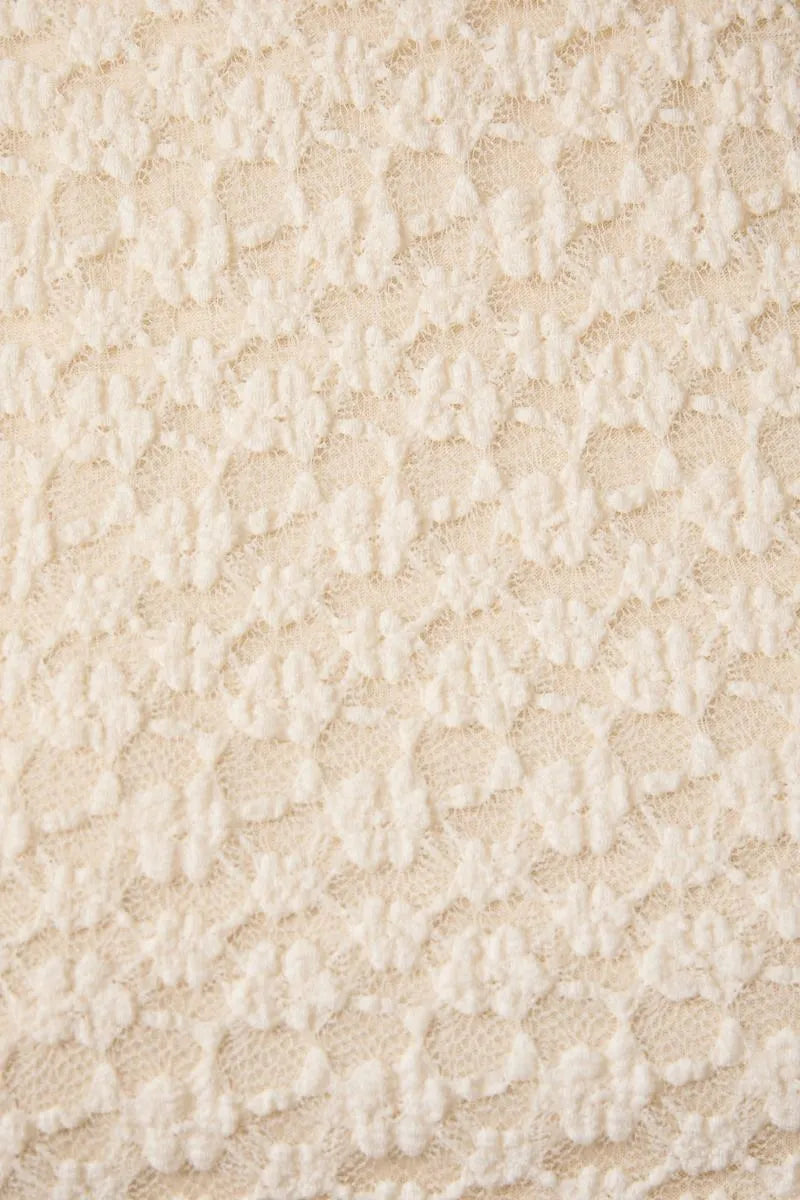 Cream-colored round neck lace sleeveless top featuring delicate raised floral lace fabric pattern