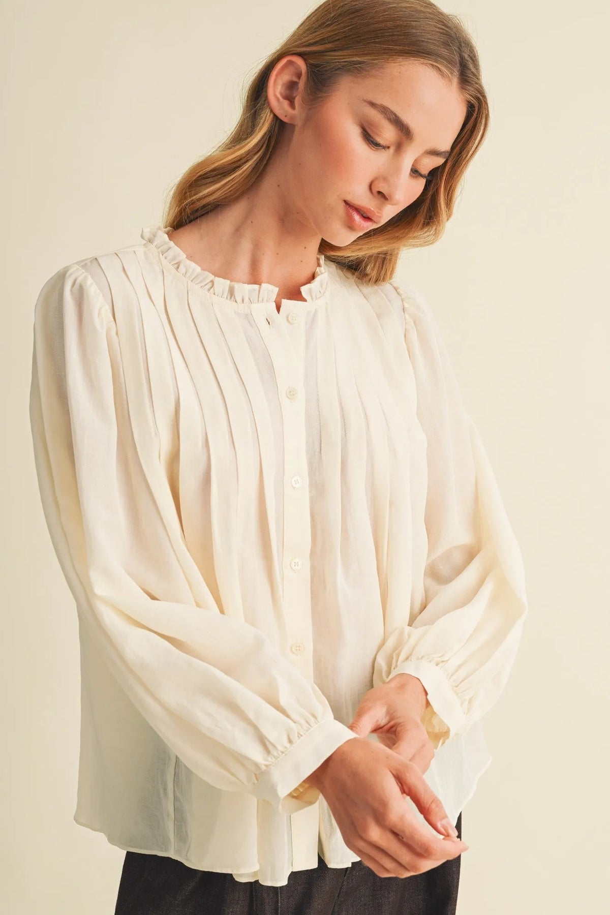 Cream-colored lightweight blouse with pintuck bib ruffle collar and long sleeves featuring a ruffle collar detail