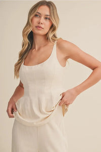 Cream-colored lightweight linen tank top with scoop neck zipper and subtle peplum hem in front view