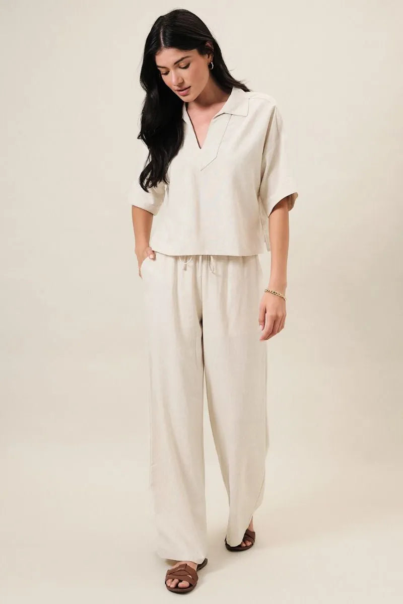 Cream-colored wide linen pants with elastic waist drawstring and back patch pocket in relaxed wide linen pants style