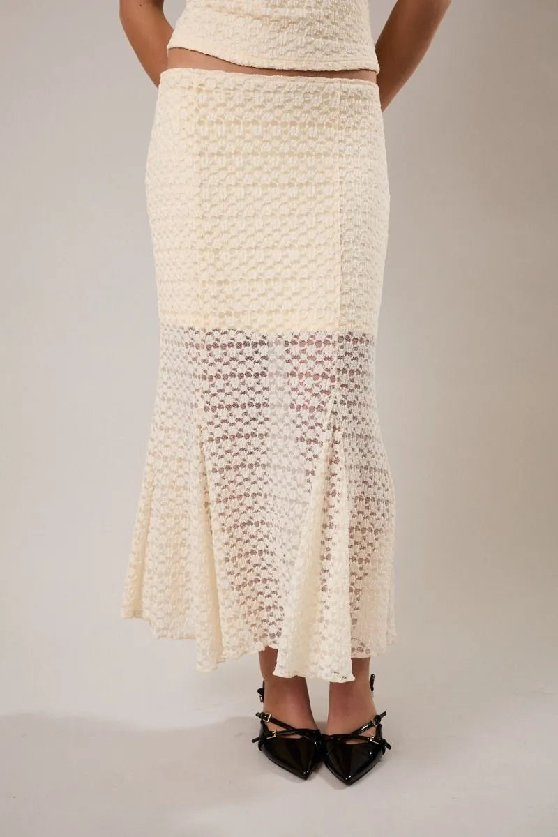 Cream-colored mid rise midi skirt with textured woven upper section and delicate lace detailing at the hem