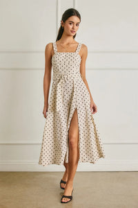 A cream-colored linen polka dot midi dress with a square neckline, thin straps, and a buckle belt at the waist