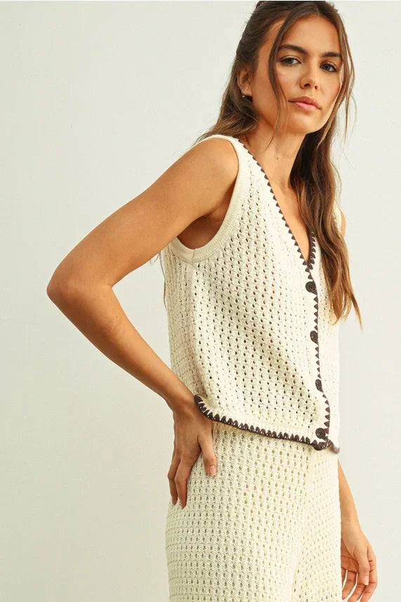 Cream-colored crochet knit vest with black trim and button details