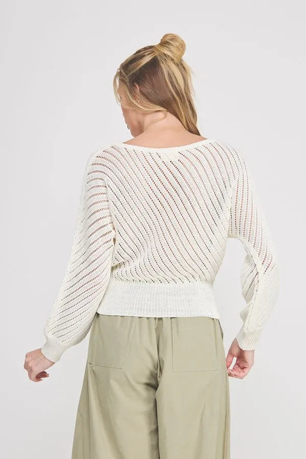 A cream-colored hand yarn open stitch dolman sweater top with long sleeves and ribbed waistband