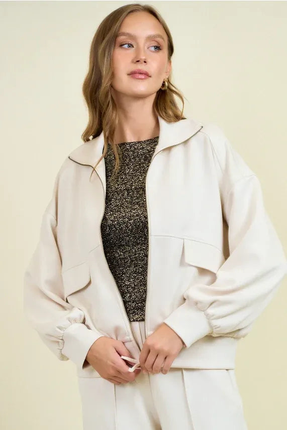 Cream-colored buttery soft flap pocket jacket with oversized bomber style and subtle contrast stitching in relaxed fit
