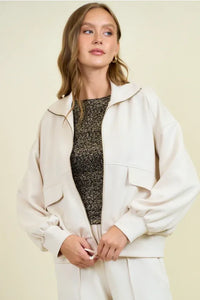 Cream-colored buttery soft flap pocket jacket with oversized bomber style and subtle contrast stitching in relaxed fit