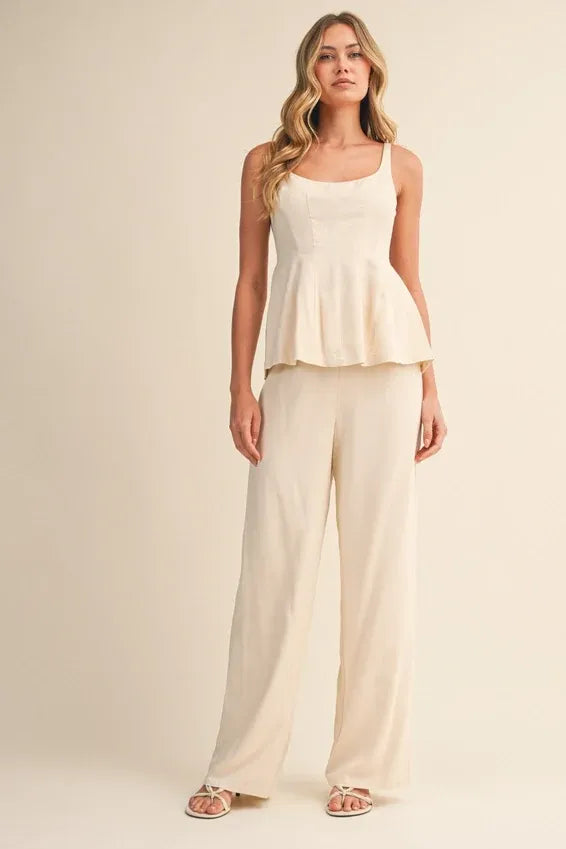 Cream-colored scoop neck zipper back blouse with thin straps and flowing peplum fabric for elegant wear