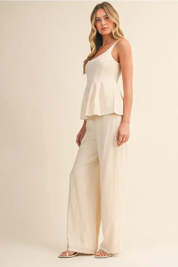 Cream-colored scoop neck zipper back blouse with lightweight peplum fabric and delicate spaghetti straps