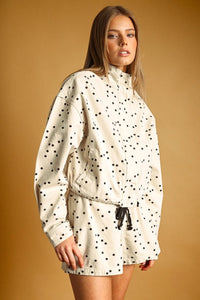 Cream-colored polka dot high neck utility jacket with black dots and adjustable drawstring waist for versatile wear