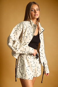 Cream-colored polka dot high neck utility jacket with black dots and drawstring waist for versatile wear
