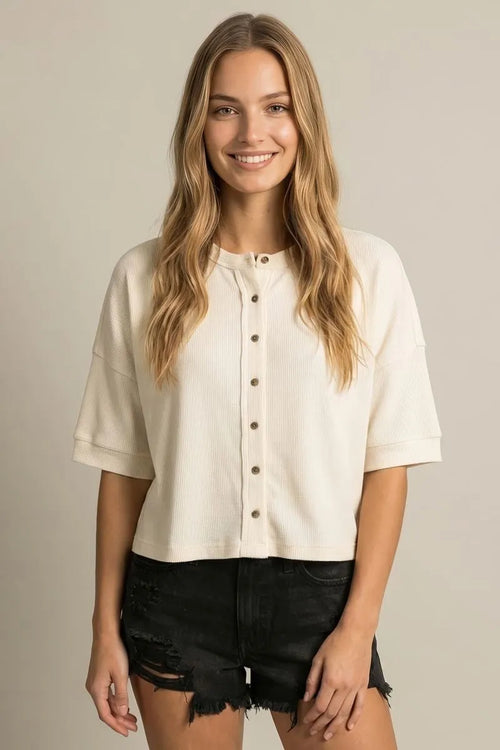 Cream-colored ribbed knit round neck boxy knit cardigan with short sleeves and relaxed fit button-up front