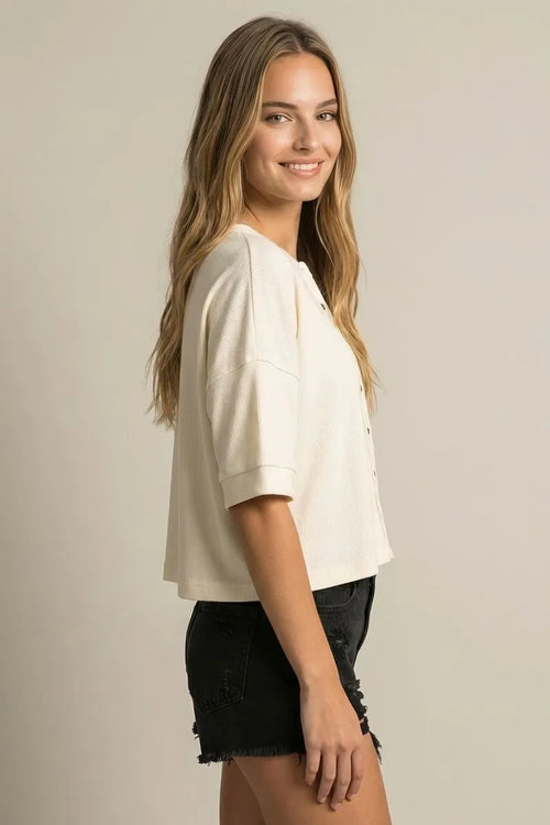 Cream-colored ribbed knit cropped top with short sleeves and button-front design for round neck boxy knit cardigan style