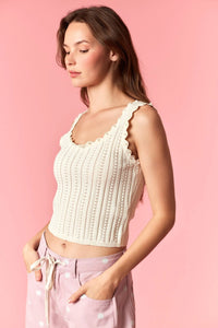 Cream-colored ribbed knit crop top with scalloped edge and pearl studs knit detailing for elegant wear